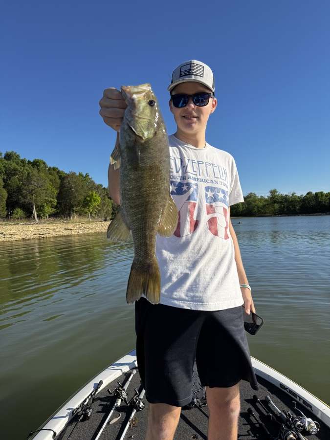 Aaron with a smallmouth off a rip-rap bank on a bluebird day.